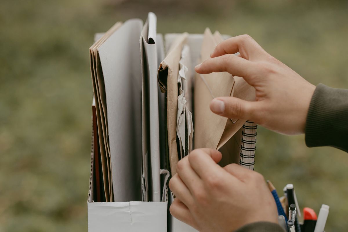 Mãos organizando pastas e envelopes de documentos